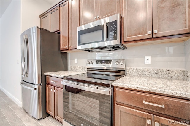 kitchen with tasteful backsplash, light stone countertops, and stainless steel appliances