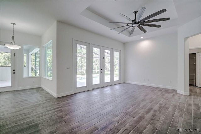 unfurnished living room with french doors, a raised ceiling, and ceiling fan