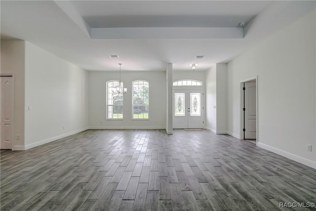 entryway with french doors, a raised ceiling, and a notable chandelier