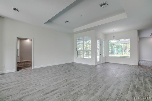 unfurnished living room featuring a tray ceiling and light hardwood / wood-style floors