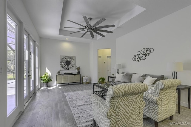 living room featuring ceiling fan, a raised ceiling, and french doors