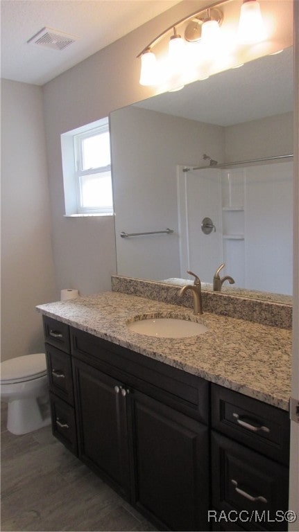 bathroom with a shower, vanity, and toilet