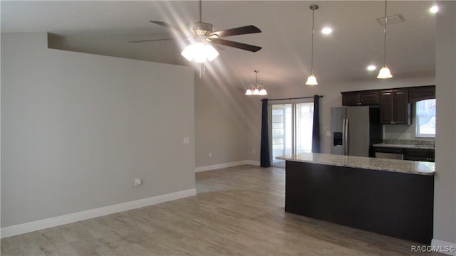 kitchen with light stone countertops, hanging light fixtures, stainless steel fridge with ice dispenser, dark brown cabinets, and light wood-type flooring