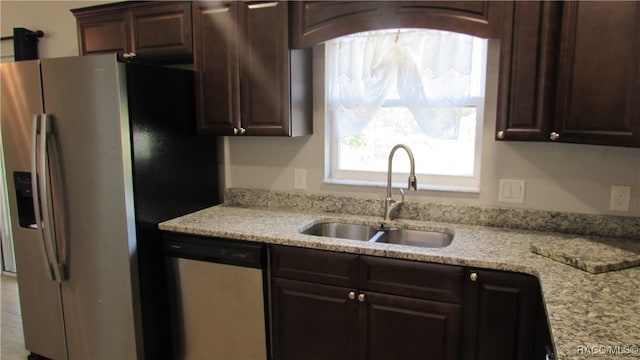 kitchen with light stone countertops, sink, stainless steel appliances, and dark brown cabinets