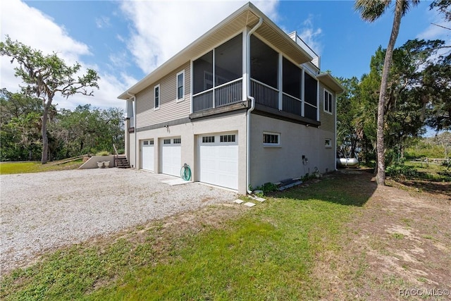 14211 W Saint Martins Rd, Crystal River, FL 34429 - view of property exterior featuring a sunroom, stucco siding, a lawn, a garage, and driveway