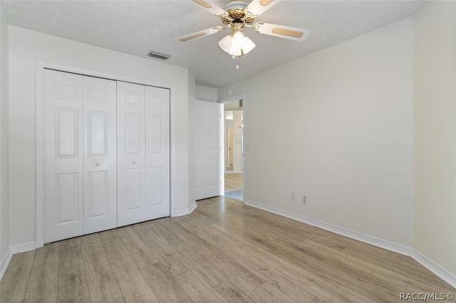 unfurnished bedroom featuring ceiling fan, a closet, light hardwood / wood-style floors, and a textured ceiling