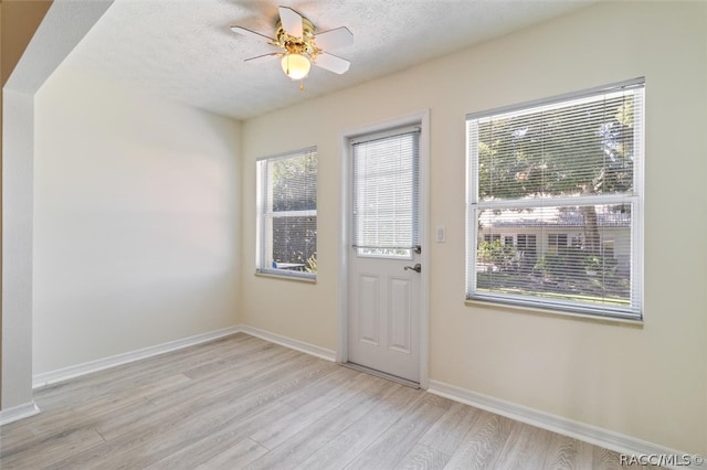 entryway with ceiling fan, light wood-type flooring, and a textured ceiling