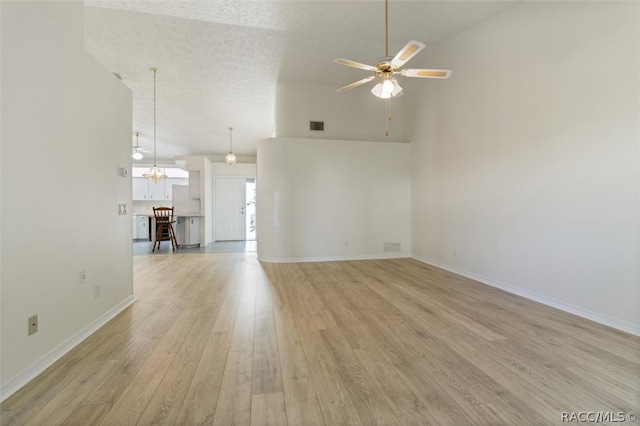 unfurnished living room featuring ceiling fan, a textured ceiling, high vaulted ceiling, and light hardwood / wood-style flooring