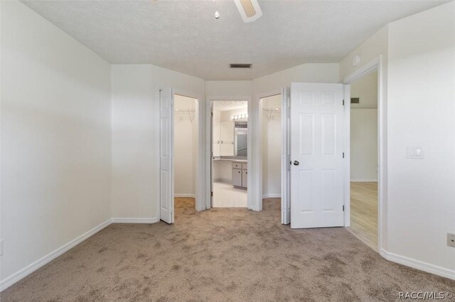 820 Inverie Dr, Inverness, FL 34453 - unfurnished bedroom featuring carpet, baseboards, connected bathroom, a walk in closet, and a ceiling fan