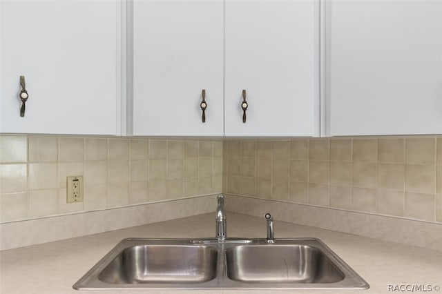 room details featuring white cabinets, backsplash, and sink