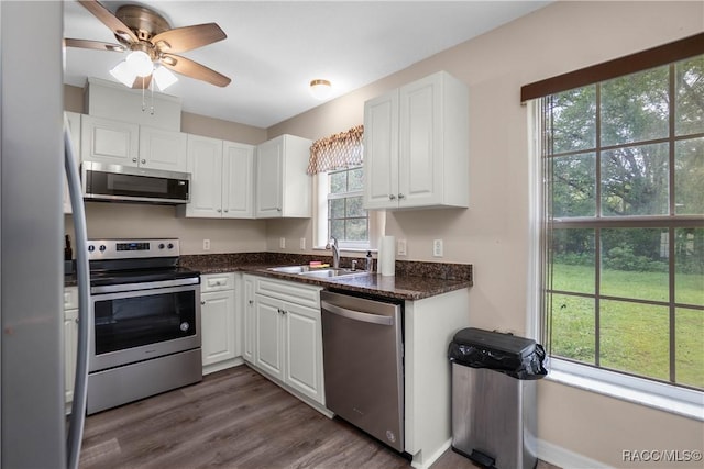 835 N Rembrandt Way, Inverness, FL 34453 - kitchen with appliances with stainless steel finishes, white cabinets, dark wood-style flooring, a ceiling fan, and dark stone countertops