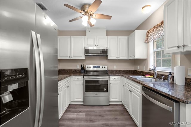 835 N Rembrandt Way, Inverness, FL 34453 - kitchen featuring stainless steel appliances, white cabinets, a ceiling fan, dark wood-style flooring, and dark stone countertops