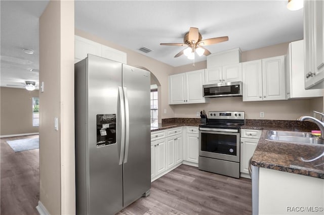 835 N Rembrandt Way, Inverness, FL 34453 - kitchen featuring appliances with stainless steel finishes, ceiling fan, white cabinetry, light wood-type flooring, and arched walkways