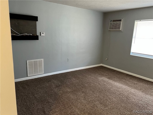 carpeted spare room with a wall mounted air conditioner and a textured ceiling