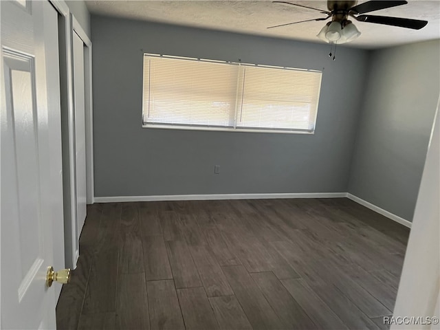 empty room with dark hardwood / wood-style flooring, ceiling fan, and plenty of natural light