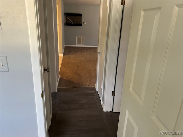 hallway featuring dark colored carpet