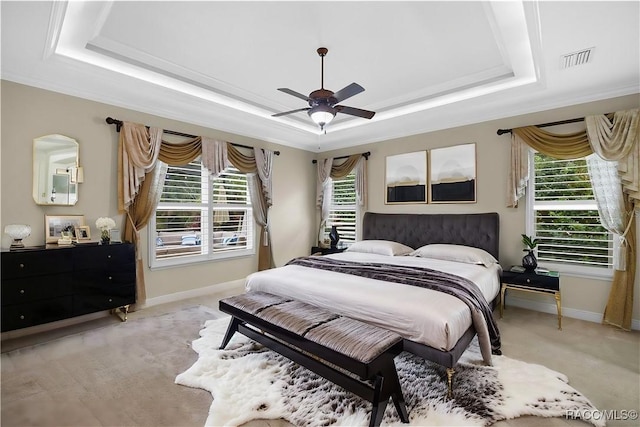 bedroom with light carpet, a tray ceiling, crown molding, and ceiling fan