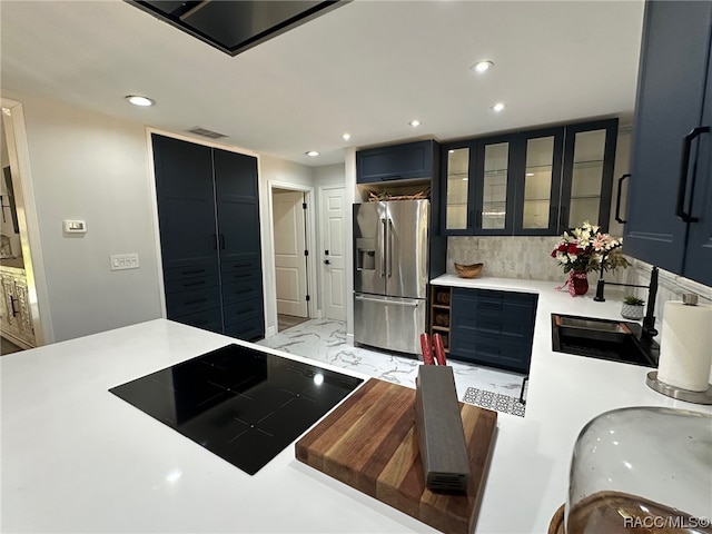 kitchen with decorative backsplash, stainless steel fridge, black electric cooktop, and sink