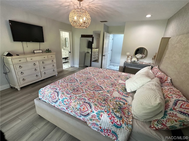 bedroom with a chandelier, wood-type flooring, and connected bathroom