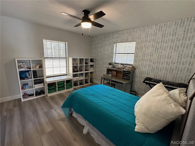 bedroom featuring ceiling fan, wood-type flooring, and a textured ceiling