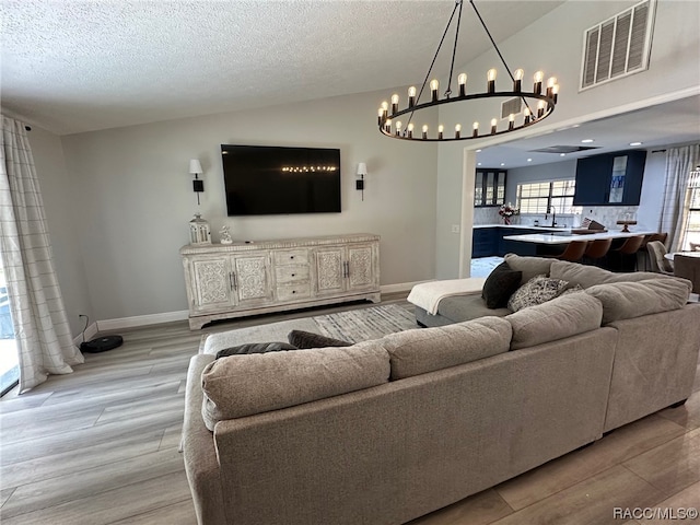 living room with a textured ceiling, light hardwood / wood-style floors, and lofted ceiling