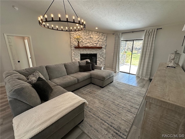 living room with hardwood / wood-style flooring, an inviting chandelier, a fireplace, and a textured ceiling