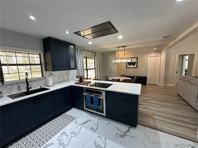 kitchen with kitchen peninsula, black cooktop, tasteful backsplash, stainless steel oven, and sink