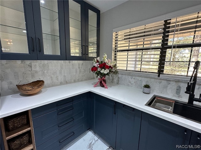 kitchen featuring decorative backsplash, blue cabinets, and sink