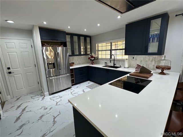 kitchen with sink, stainless steel fridge with ice dispenser, backsplash, kitchen peninsula, and black range