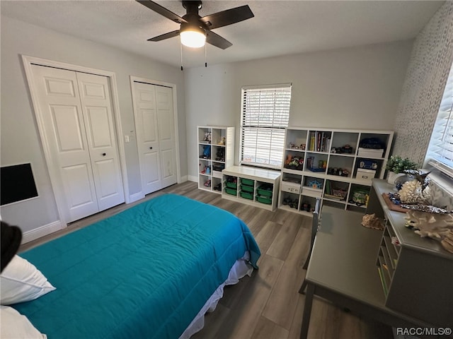 bedroom featuring a textured ceiling, dark hardwood / wood-style flooring, two closets, and ceiling fan