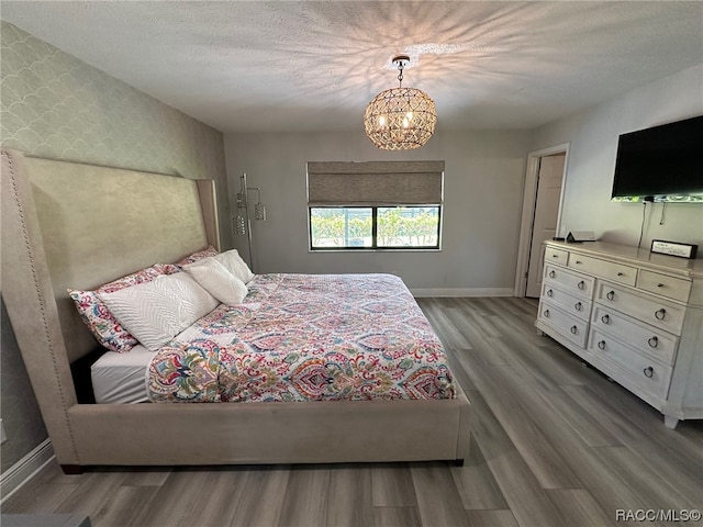 bedroom with hardwood / wood-style floors, a chandelier, and a textured ceiling