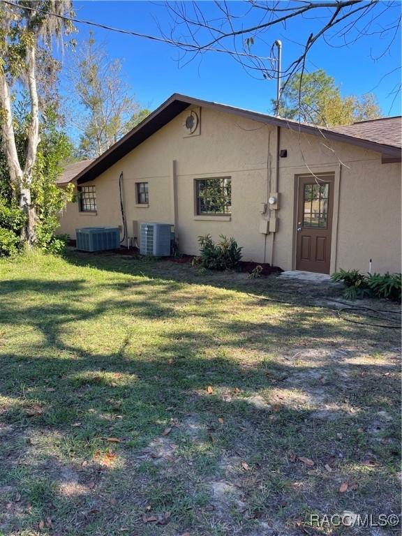 rear view of property featuring central AC unit and a yard