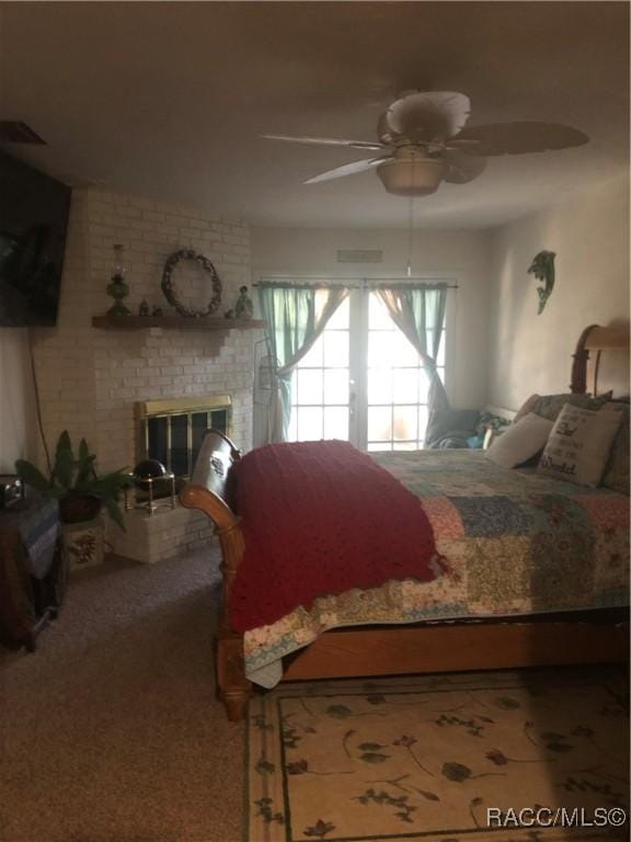 carpeted bedroom with ceiling fan and a fireplace