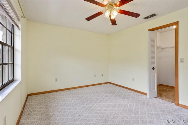 5761 S Eaton Ter, Inverness, FL 34452 - unfurnished bedroom with a walk in closet, light carpet, baseboards, a ceiling fan, and a closet