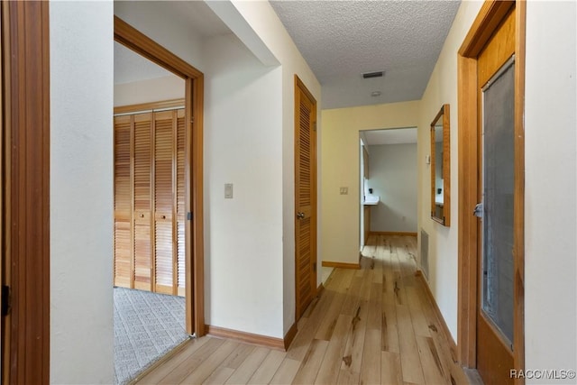 5761 S Eaton Ter, Inverness, FL 34452 - hallway featuring light wood finished floors, baseboards, and a textured ceiling