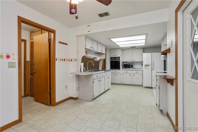 5761 S Eaton Ter, Inverness, FL 34452 - kitchen with black oven, white fridge with ice dispenser, stainless steel microwave, ceiling fan, and light countertops