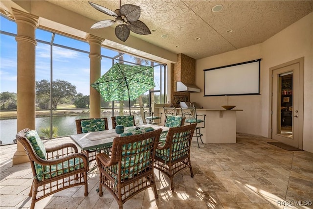 sunroom / solarium with ceiling fan and a water view