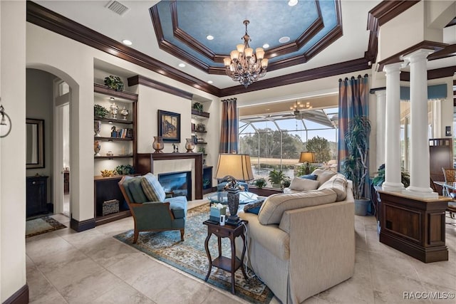 living room with an inviting chandelier, ornamental molding, a tray ceiling, and decorative columns