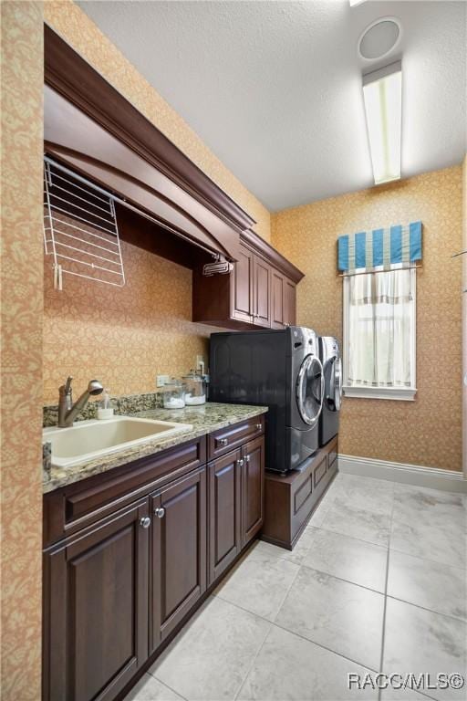 clothes washing area featuring cabinets, sink, and washing machine and clothes dryer