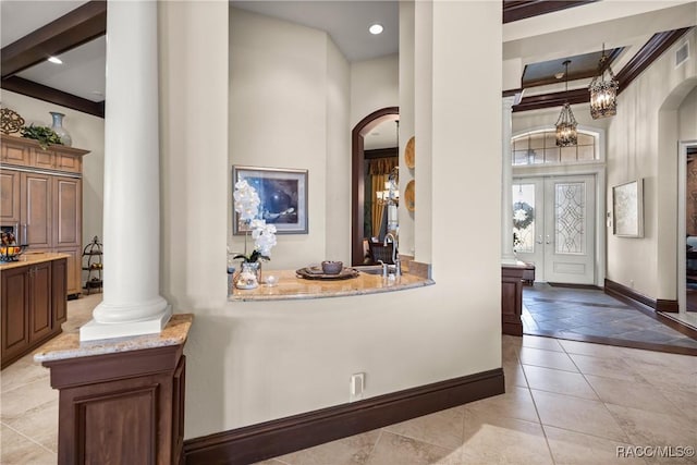 foyer entrance featuring light tile patterned floors, sink, french doors, beamed ceiling, and ornate columns