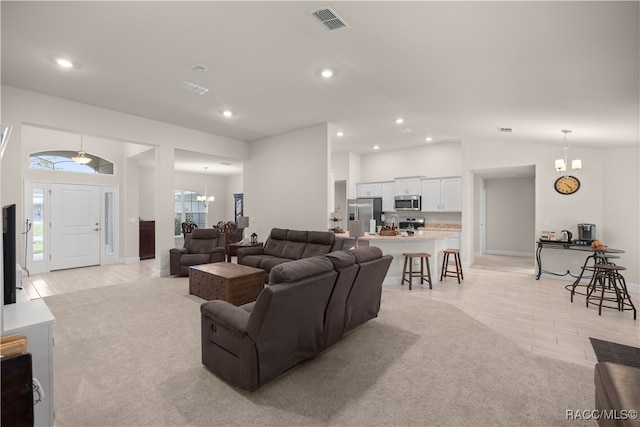 living room featuring an inviting chandelier, light hardwood / wood-style floors, vaulted ceiling, and a wealth of natural light