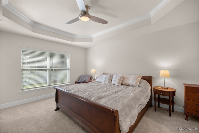 carpeted bedroom with ceiling fan, a raised ceiling, and ornamental molding