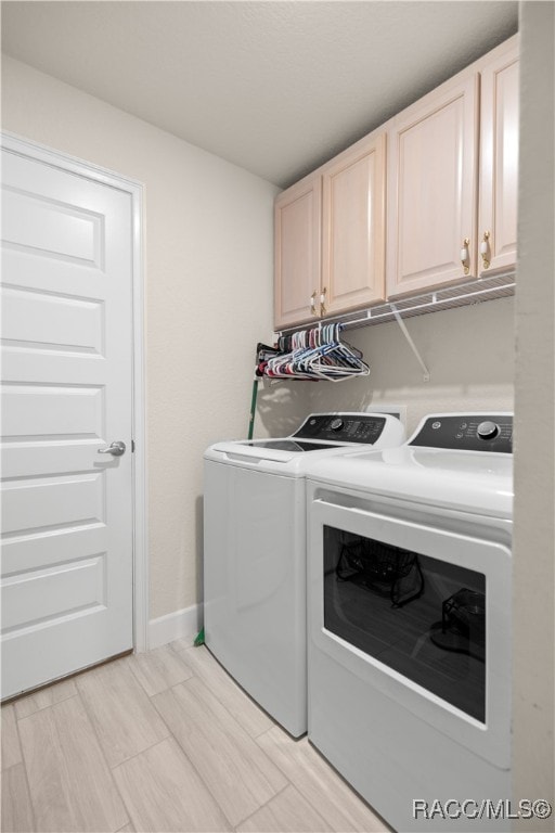 clothes washing area with washing machine and dryer and cabinets