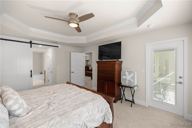 carpeted bedroom featuring access to outside, ceiling fan, a barn door, ornamental molding, and a tray ceiling