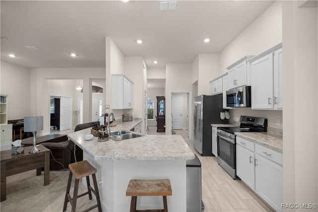 kitchen with white cabinetry, sink, kitchen peninsula, a breakfast bar area, and appliances with stainless steel finishes