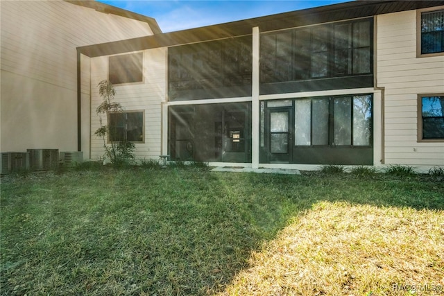 rear view of house with a lawn, central AC, and a sunroom