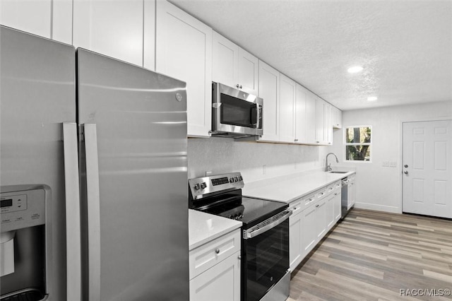 383 S Rooks Ave, Inverness, FL 34453 - kitchen featuring a textured ceiling, appliances with stainless steel finishes, white cabinetry, a sink, and light wood-style floors