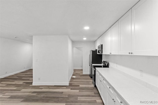 383 S Rooks Ave, Inverness, FL 34453 - kitchen with light countertops, white cabinetry, wood finished floors, stainless steel microwave, and electric range