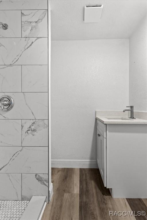 383 S Rooks Ave, Inverness, FL 34453 - bathroom with vanity, baseboards, wood finished floors, and tiled shower