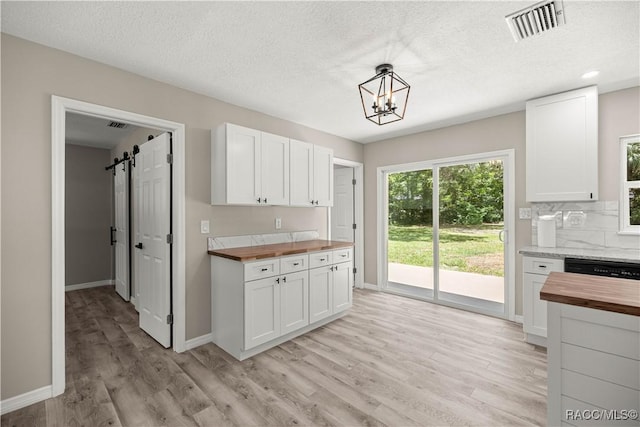 1361 NW 19th St, Crystal River, FL 34428 - kitchen with wood counters, light wood-style flooring, white cabinetry, a chandelier, and a barn door